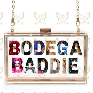 Op de afbeelding: Een doorzichtige rechthoekige clutch met een gouden kettingriem. Het woord "BODEGA BADDIE" staat in het midden, met afbeeldingen van vrouwen die elke letter vullen. De clutch heeft een gouden sluiting.