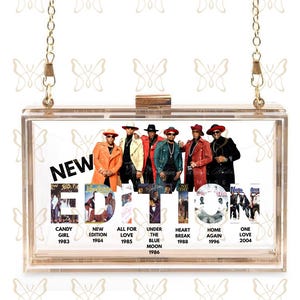 May include: Clear acrylic clutch with a gold chain strap. The clutch features a graphic of a music group with the text "NEW EDITION" and album titles and years. The clutch has a rectangular shape and a gold clasp.