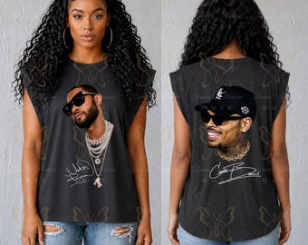 May include: Dark gray sleeveless shirt featuring a portrait of a man wearing sunglasses and jewelry. The shirt has a signature below the portrait. The back of the shirt features a different portrait of a man wearing a cap and sunglasses, with a signature.