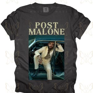 May include: A dark grey t-shirt with a white graphic of Post Malone sitting in a car. The text "Post Malone" is printed in yellow on the shirt.