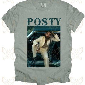 May include: A light gray t-shirt with a graphic print of a man in a white suit sitting in a vintage car. The text "POSTY" is printed in dark blue letters above the image.