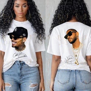 May include: A white short-sleeve t-shirt featuring a graphic print of a man wearing a black cap and sunglasses on the front, and a different man wearing sunglasses and layered gold chains on the back, both with a signature printed below.
