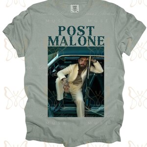 May include: A light gray t-shirt with a graphic print of Post Malone sitting in a car. The text "Post Malone" is printed in dark blue letters on the shirt.