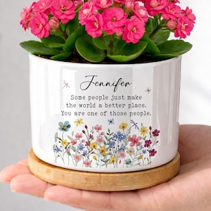 May include: A white ceramic planter with a bamboo base containing a vibrant pink Kalanchoe plant. The planter features the text "Jennifer" and "Some people just make the world a better place. You are one of those people." with colorful floral illustrations.