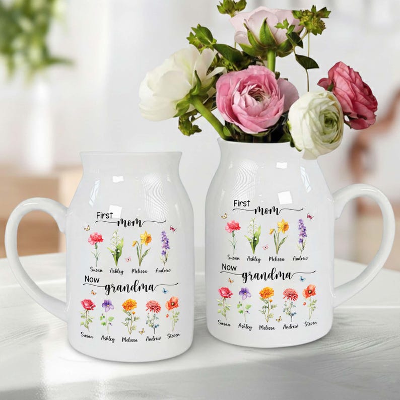 Pu&ograve; includere: Due vasi in ceramica bianca, uno a forma di tazza e l'altro a forma di brocca, adornati con illustrazioni floreali e la scritta "First mom, Now grandma". I vasi sono pieni di fiori colorati.