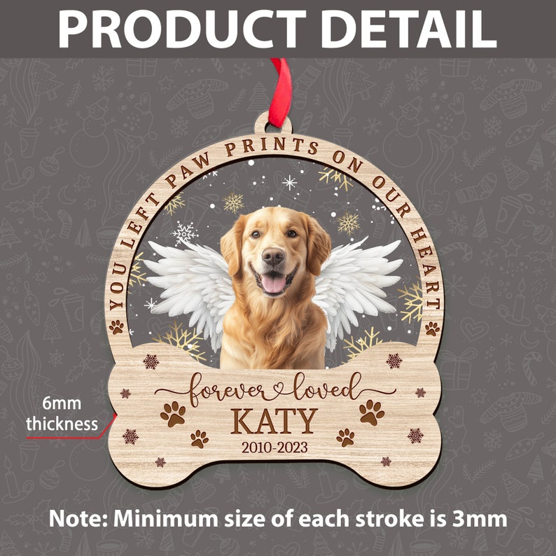 May include: A wooden Christmas ornament shaped like a bone with a golden retriever dog with angel wings inside a circle. The ornament has the text "You left paw prints on our heart" and "forever loved KATY 2010-2023". The ornament is 6 mm thick.