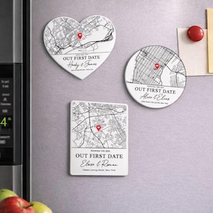May include: Three white ceramic magnets with black map designs and red heart markers. One is heart-shaped, another round, and the third rectangular. Each magnet has the text "OUT FIRST DATE" and names, with a date and location.