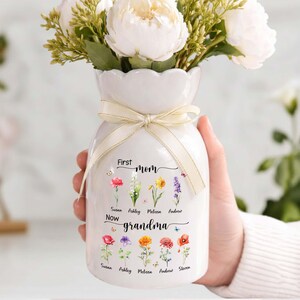 Pu&ograve; includere: Vaso in ceramica bianca con un nastro color crema, con fiori bianchi. Il vaso &egrave; decorato con illustrazioni floreali e le parole "First Mom Now Grandma" con nomi sotto.
