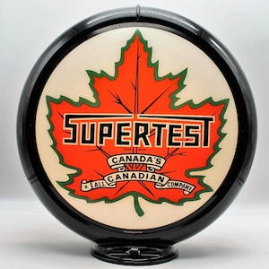 Puede incluir: Un letrero de gasolinera Supertest vintage. El letrero presenta una gran hoja de arce naranja con la palabra "SUPERTEST" en letras negras. También es visible el texto "CANADA'S ALL CANADIAN COMPANY". El letrero tiene un borde y una base negros.