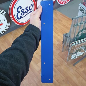 K&ouml;nnte beinhalten: Ein langes, schmales, blaues Metallwinkelst&uuml;ck mit f&uuml;nf gebohrten L&ouml;chern. Das Winkelst&uuml;ck wird in der Hand einer Person gehalten.