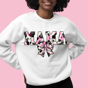 May include: White sweatshirt with the word "MAMA" in black letters with a pink and black animal print design. A pink and black bow is below the word.