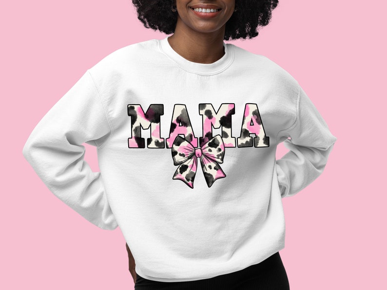 May include: White sweatshirt with the word "MAMA" in black letters with a pink and black animal print design. A pink and black bow is below the word.