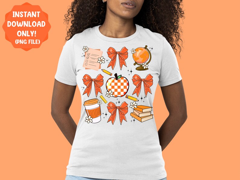 May include: White t-shirt with a design of orange and white bows, a red apple, a globe, a pencil, a coffee cup, and a stack of books. The design is surrounded by small white flowers.