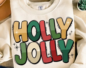 Puede incluir: Una sudadera de color crema con las palabras "HOLLY JOLLY" en una fuente de estilo retro. Las letras están delineadas en negro y rellenas con tonos de verde, rojo, amarillo y beige.
