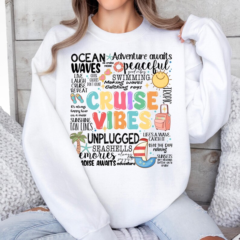 Peut inclure: Sweat-shirt blanc avec un motif graphique color&eacute; comportant les mots "Ocean Waves", "Cruise Vibes", "Unplugged", "Seashells", "Memories", et "Paradise Awaits". Le motif comprend &eacute;galement une vari&eacute;t&eacute; d'images nautiques et tropicales, telles que des palmiers, des coquillages et une valise.