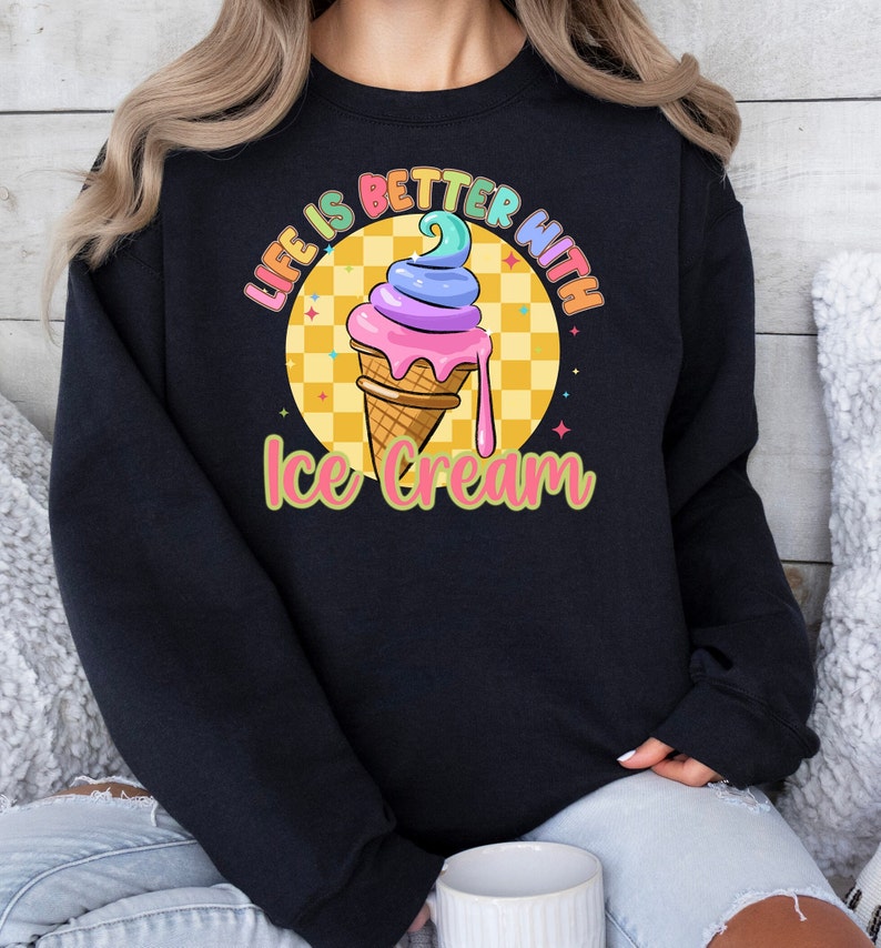 Puede incluir: Sudadera negra con un gr&aacute;fico de un cono de helado colorido y el texto "Life is better with ice cream".