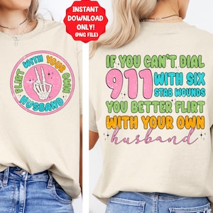 May include: A light beige t-shirt with a graphic print on the front and back. The front graphic is a circle with a skeleton hand making a peace sign and the text "Flirt with your own husband". The back graphic has the text "If you can't dial 911 with six stab wounds you better flirt with your own husband".