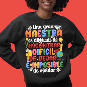 Op de afbeelding: Zwart sweatshirt met een kleurrijke grafische print met de tekst "Una gran MAESTRA es difficult de ENCONTRAR DIFCIL DE DEJAR IMPOSIBLE de olvidar".