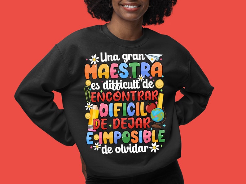 Op de afbeelding: Zwart sweatshirt met een kleurrijke grafische print met de tekst "Una gran MAESTRA es difficult de ENCONTRAR DIFCIL DE DEJAR IMPOSIBLE de olvidar".