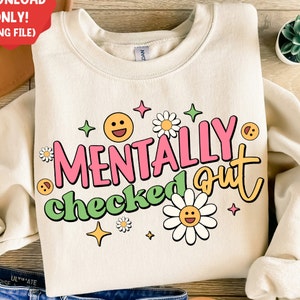 May include: A beige sweatshirt with the text "Mentally checked out" in pink, green, and yellow letters. The text is surrounded by cartoon flowers and stars.