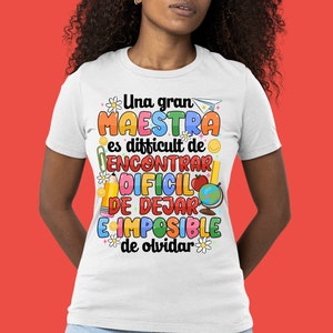 Op de afbeelding: Wit T-shirt met een kleurrijke afbeelding met de tekst "Una gran maestra es difficult de encontrar, dificil de dejar, e imposible de olvidar".