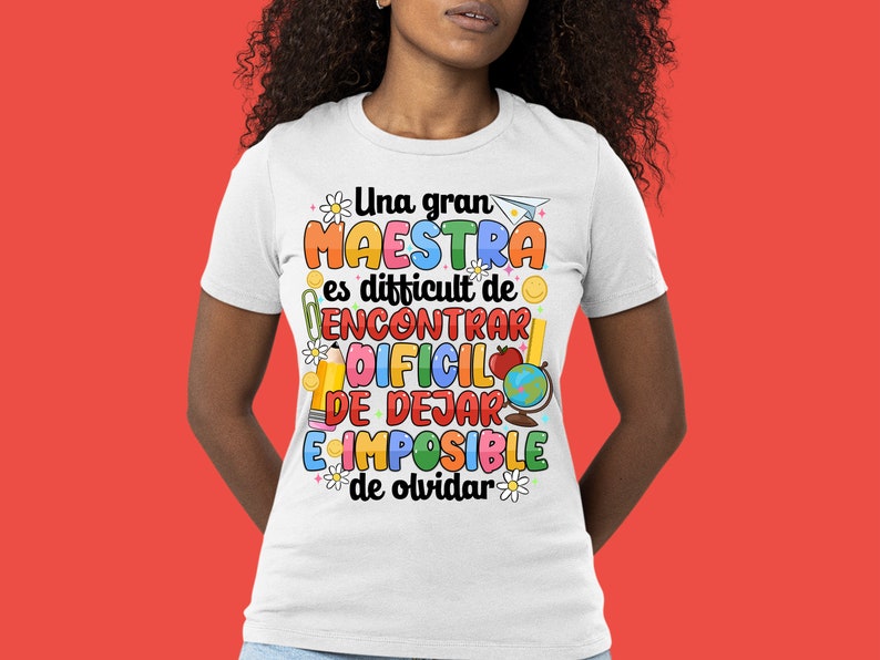 Op de afbeelding: Wit T-shirt met een kleurrijke afbeelding met de tekst "Una gran maestra es difficult de encontrar, dificil de dejar, e imposible de olvidar".