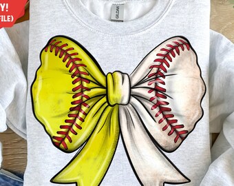 Puede incluir: Una sudadera gris con un gran diseño de lazo de softball amarillo y blanco. El lazo está hecho para parecerse a una pelota de softball con costuras rojas.