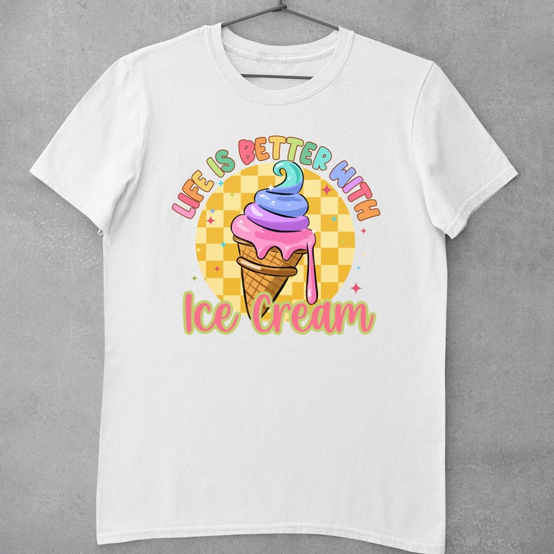Puede incluir: Camiseta blanca con un gr&aacute;fico de cono de helado colorido y el texto "Life is better with ice cream".