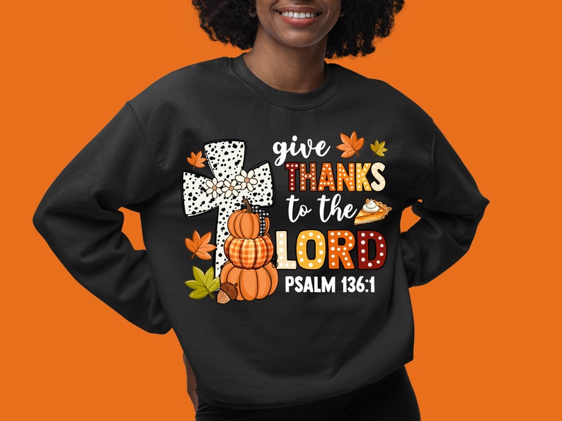 May include: Black sweatshirt with a white and black cross, pumpkins, and fall leaves. The text reads "give THANKS to the LORD PSALM 136:1".