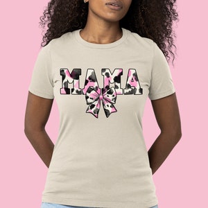 May include: A white t-shirt with the word "MAMA" printed in black and pink animal print letters. A pink and black animal print bow is below the word.