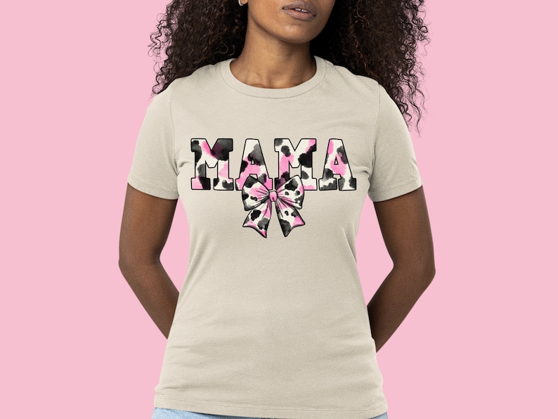 May include: A white t-shirt with the word "MAMA" printed in black and pink animal print letters. A pink and black animal print bow is below the word.