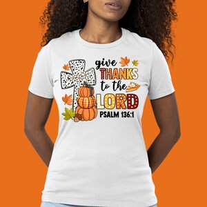 May include: White t-shirt with a graphic of a cross, pumpkins, and fall leaves. The text reads "give THANKS to the LORD PSALM 136:1".