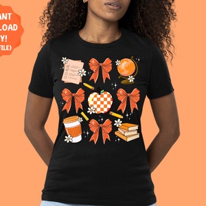 May include: A black t-shirt with a design of various school-themed items, including an apple, a globe, a pencil, a book, a coffee cup, and bows in orange and white.