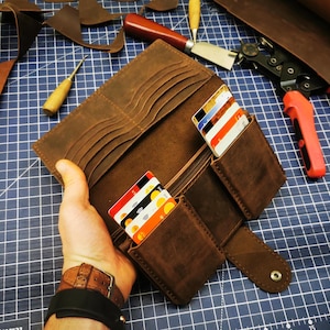 May include: A brown leather wallet with multiple card slots and a billfold. The wallet is open and has several credit cards inside.