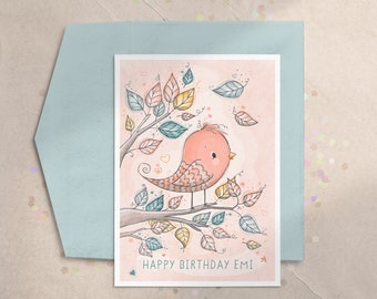 May include: A pink and white bird with a yellow beak sits on a branch with green and yellow leaves. The background is a light pink watercolor wash. The text "HAPPY BIRTHDAY EMI" is written below the bird.