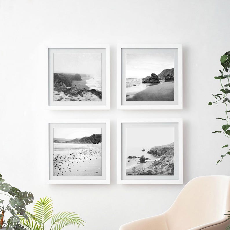 Puede incluir: Un conjunto de cuatro cuadros cuadrados con marcos blancos, cada uno con una fotograf&iacute;a de paisaje en blanco y negro de una playa costera con acantilados rocosos, orillas arenosas y olas del mar, dispuestos en una cuadr&iacute;cula de dos por dos.