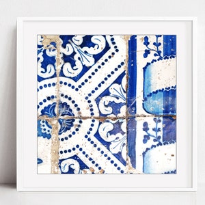 May include: A close-up of a blue and white patterned tile with a floral design. The tile is cracked and worn, giving it a vintage look.