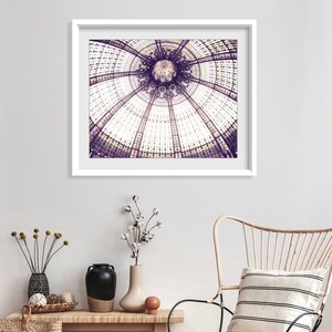 May include: A framed print of a detailed architectural ceiling with a circular design. The image is in shades of purple and white, with a white frame. The print hangs above a wooden bench with decorative vases and a woven basket.