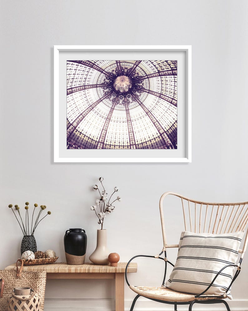 May include: A framed print of a detailed architectural ceiling with a circular design. The image is in shades of purple and white, with a white frame. The print hangs above a wooden bench with decorative vases and a woven basket.