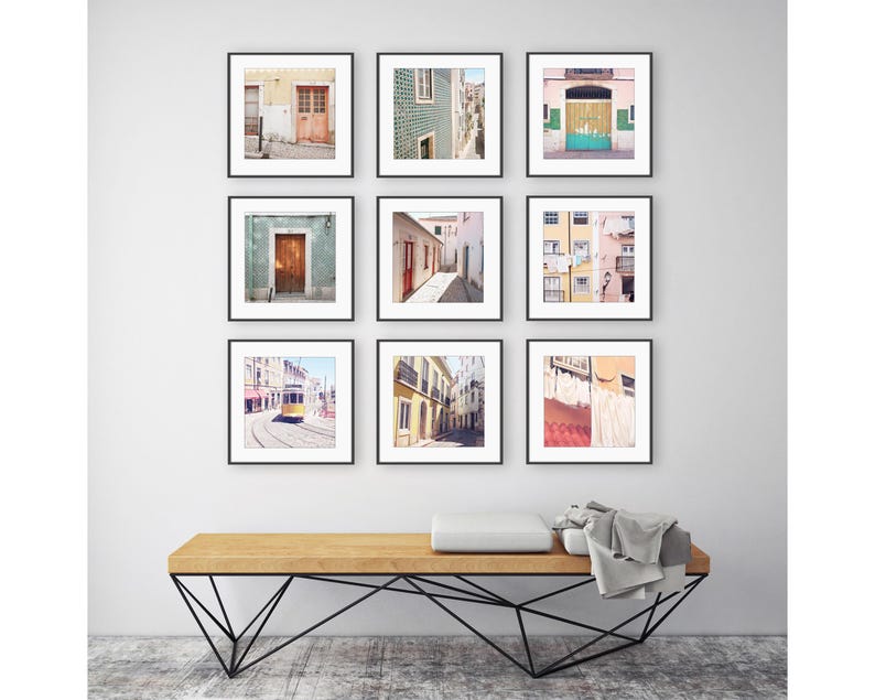 May include: Nine framed art prints featuring architectural scenes. The prints showcase colorful doors, buildings, and streets. The artwork is displayed above a wooden bench with a black metal base, creating a gallery wall aesthetic.