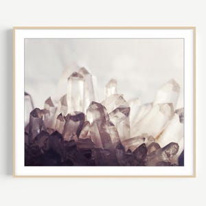 Pu&ograve; includere: Una stampa artistica incorniciata raffigurante un gruppo di cristalli di quarzo traslucidi e appuntiti. La formazione minerale presenta varie tonalit&agrave; di bianco, grigio e viola tenue, con nette sfaccettature geometriche che catturano la luce.