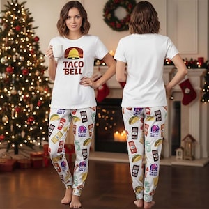 Puede incluir: Conjunto de pijama blanco con el logo de Taco Bell en la camiseta y un estampado repetido de elementos del menú de Taco Bell en los pantalones. La camiseta tiene cuello redondo y mangas cortas. Los pantalones tienen cintura con cordón y tobillos con puños. El conjunto es de material suave y cómodo.