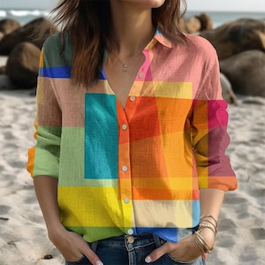 Puede incluir: Una camisa abotonada colorida con un patrón geométrico. La camisa presenta una variedad de colores, incluyendo rosa, naranja, amarillo, verde y azul. La camisa de manga larga está abierta, revelando un vistazo de una camiseta interior azul.