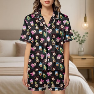 May include: Black pajama set featuring a repeating pattern of colorful cartoon characters. The short-sleeved top and shorts have white trim. The characters include Mickey Mouse, Minnie Mouse, Donald Duck, and Goofy.