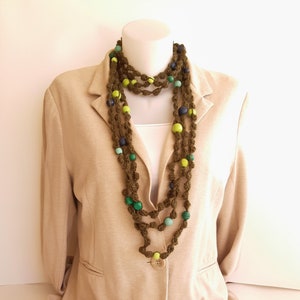 May include: A long, crocheted necklace with green, blue, and yellow beads. The necklace is layered and has a button closure.