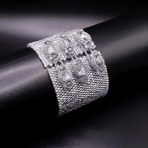 Pulseira larga com cubos prateados/cinza-claros brilhantes, fecho de botão e argolas com miçangas integradas. Pulseira tecida com cristais S-430