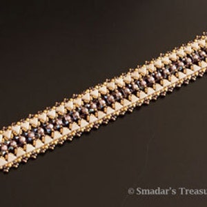 May include: A gold and white beaded bracelet with a geometric pattern. The bracelet is made with small, round beads and has a toggle clasp.