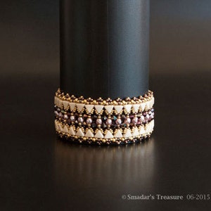 May include: A beaded bracelet with a geometric pattern in shades of brown, white, and pink. The bracelet is made with small, round beads and has a delicate, feminine look.