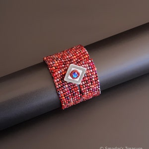 Bracciale con perline scintillanti rosso rubino e blu con chiusura a bottone quadrato in argento anticato e cristallo blu zaffiro. Bracciale intrecciato testurizzato S-479