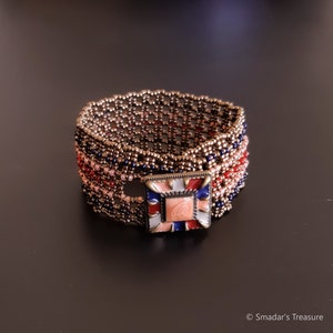 May include: A beaded bracelet with a square-shaped, multi-coloured, enamel charm. The bracelet is made with brown, pink, red, and blue beads.
